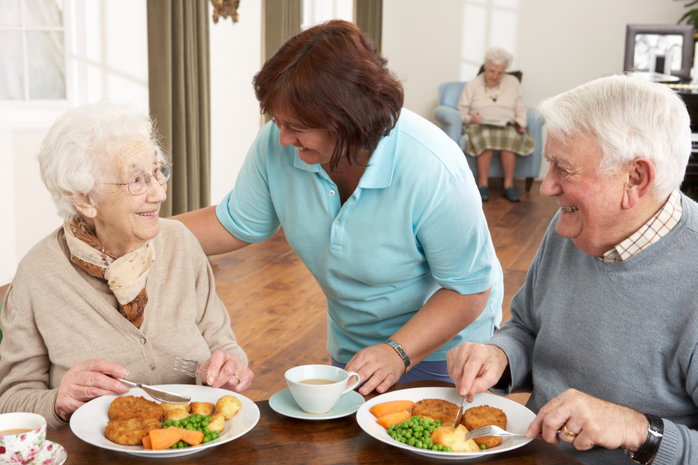 elderly couple enjoying a meal with caregiver