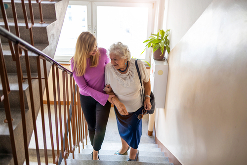 Caregiver helping senior with dementia walk up stairs