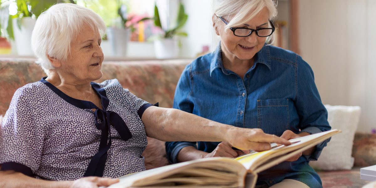 caregiver and senior with dementia reading a book