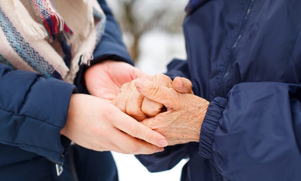 senior holding hands with caregiver in the winter snow
