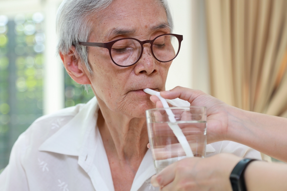 caregiver assisting senior with drinking water